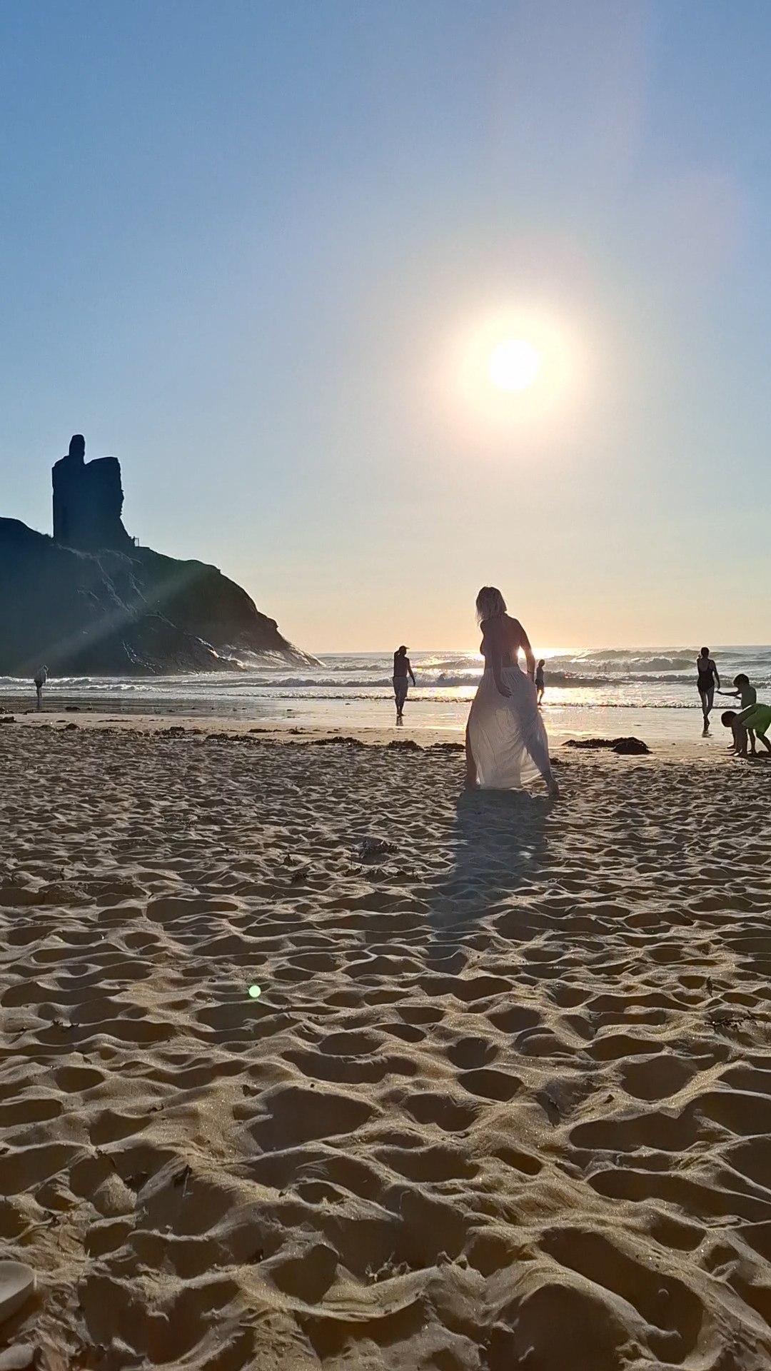 Jacqui walking on Ballybunion beach at sunset with castle silhouette